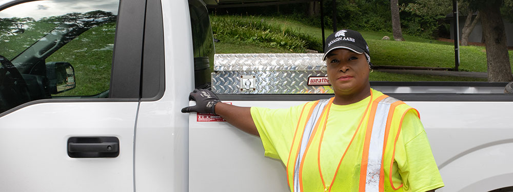 A woman standing by a truck in her work uniform.