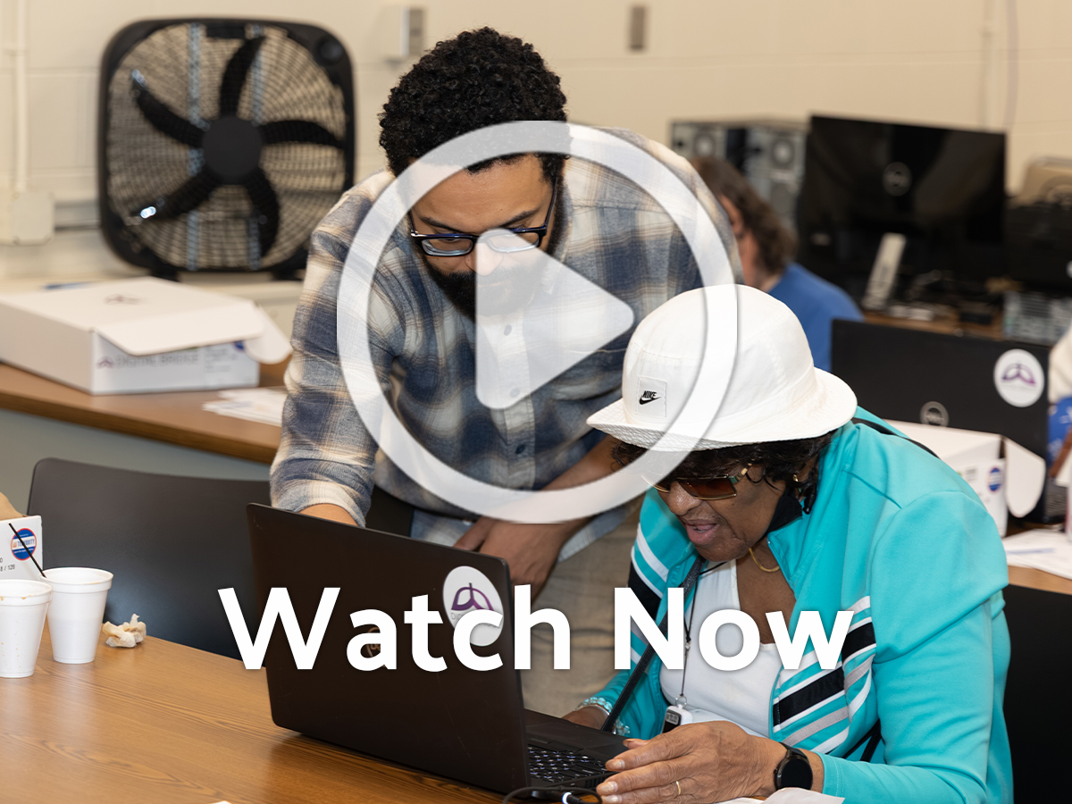 Two people at computer with overlay play button
