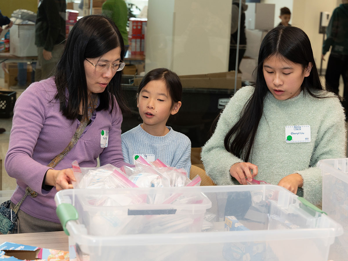 Mother and daughters packing food kits