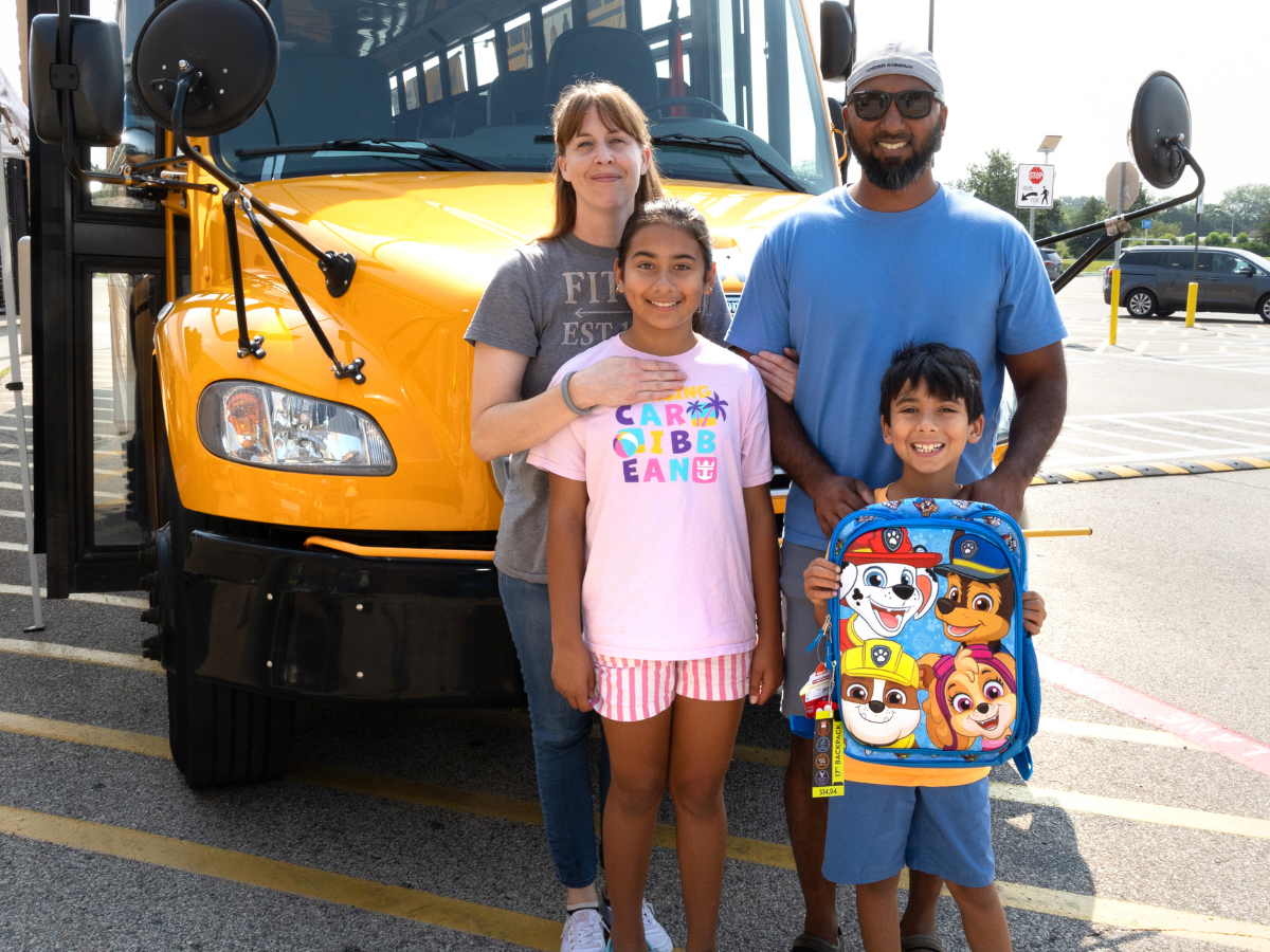 Image of family with backpack in from of bus