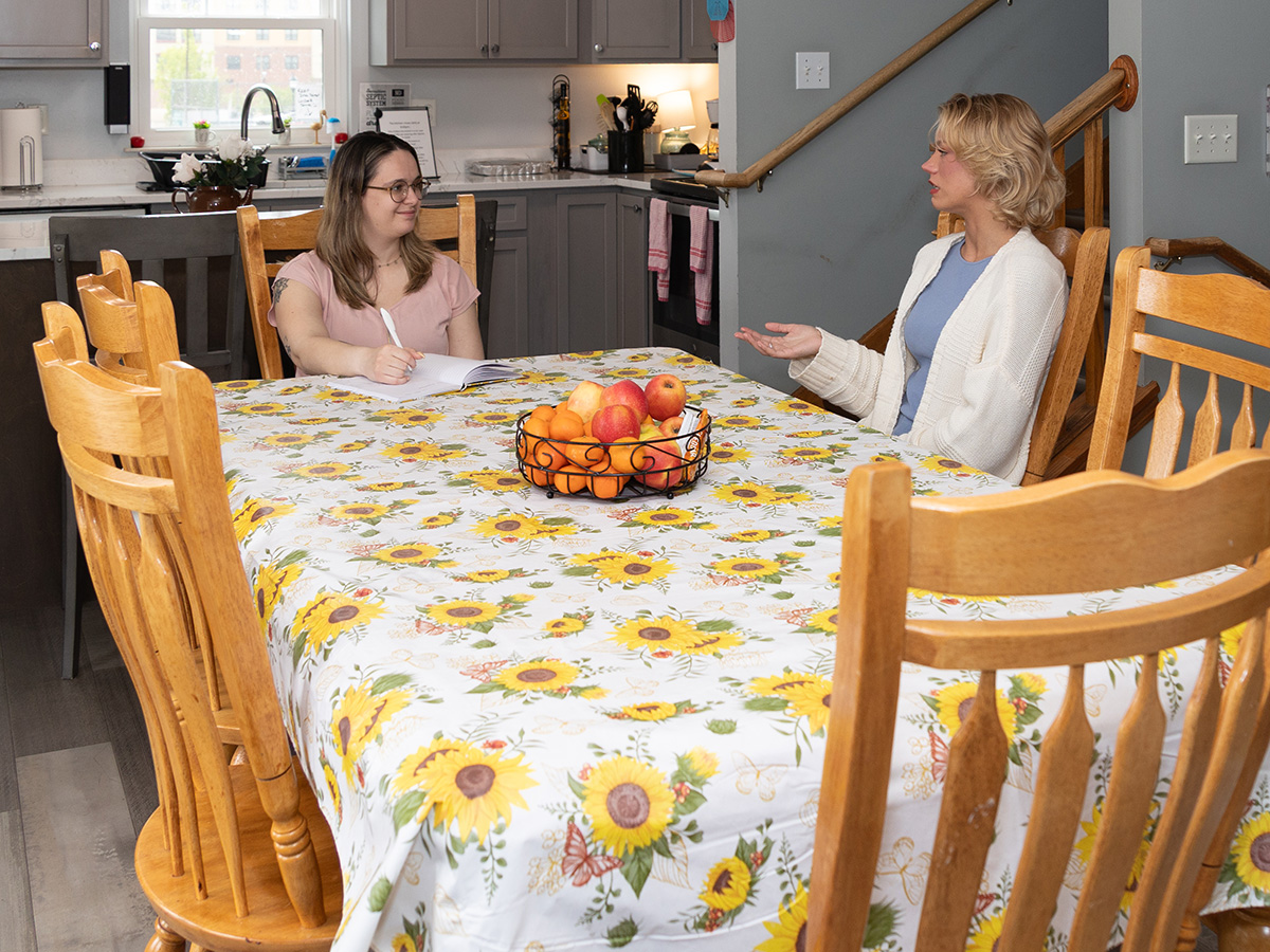 Two women sitting at a kitchen table talking