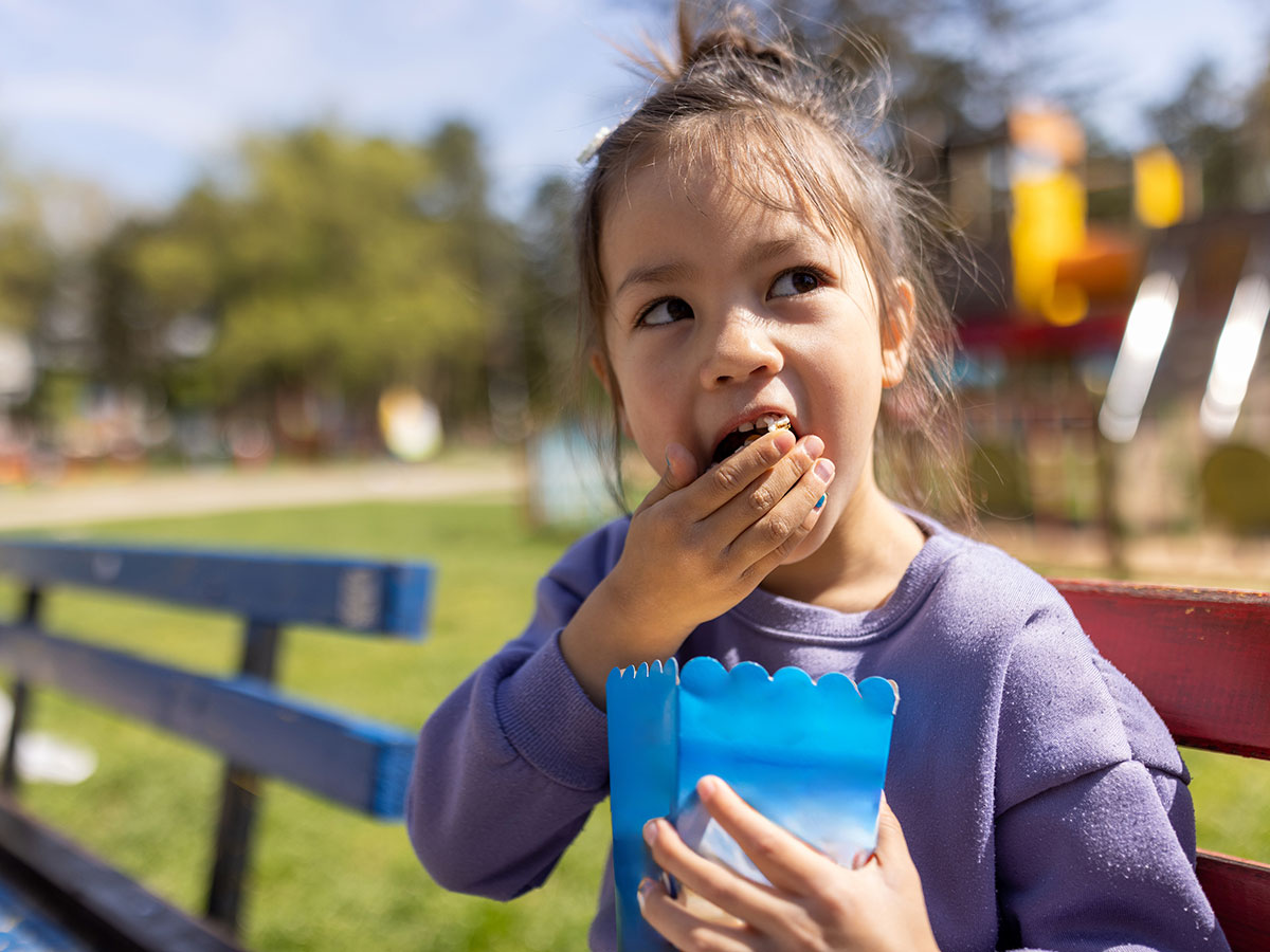 girl eating snack on park bench