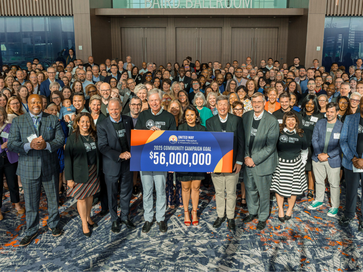 large group of people holding sign that says 2025 Community Campaign Goal $56,000,000