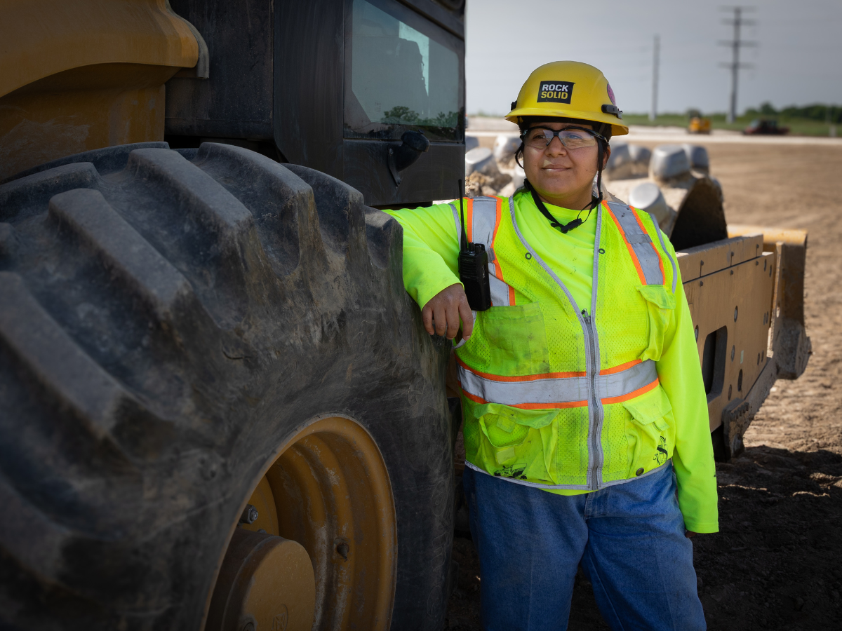 Woman in work clothes by a tire.