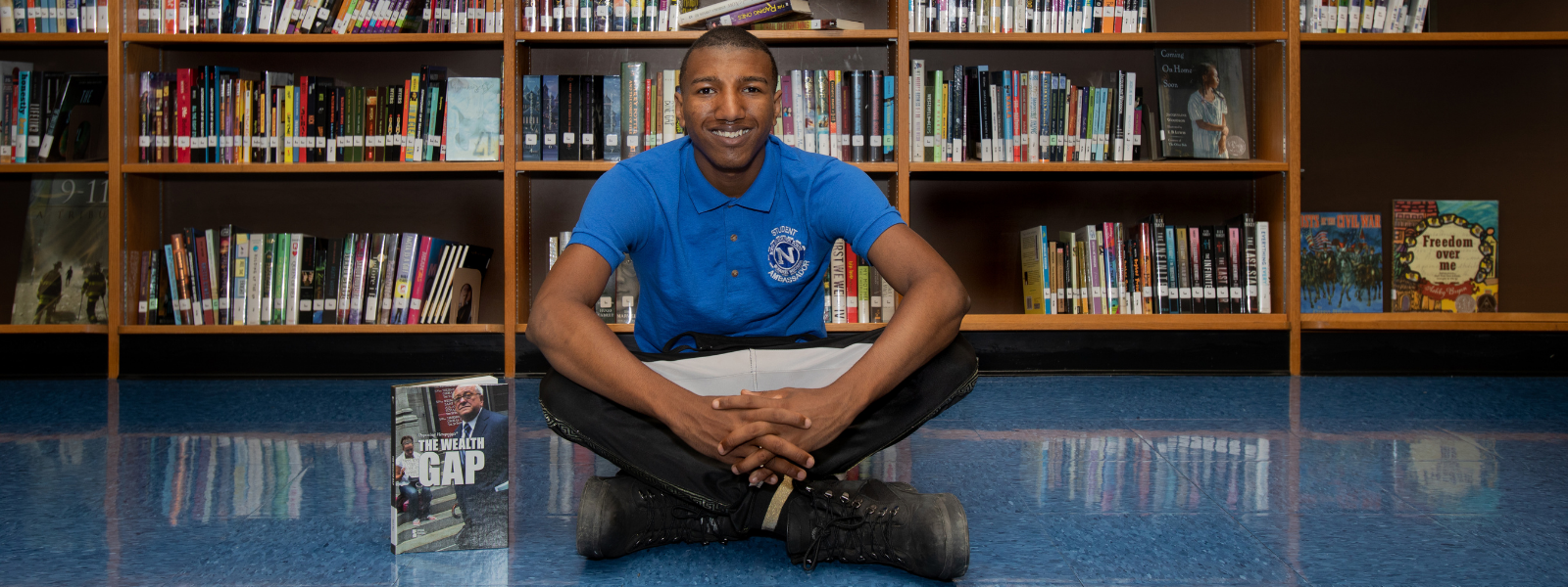 Malkeak sitting in front of bookshelves