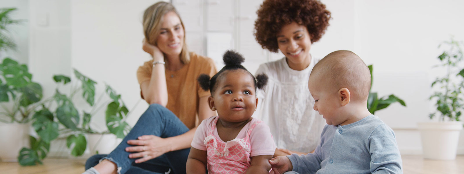 image of two babies and to mothers sitting on the floor playing