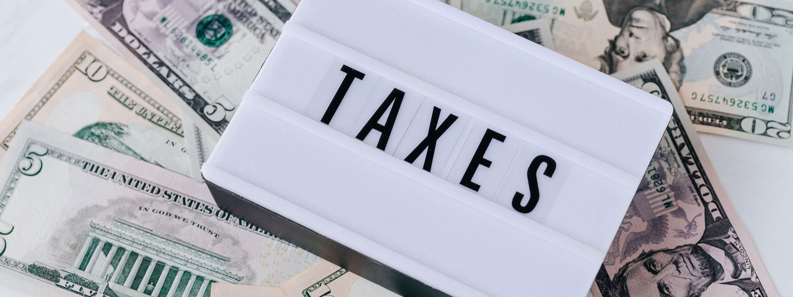 Image of sign saying taxes and dollar bills under the sign