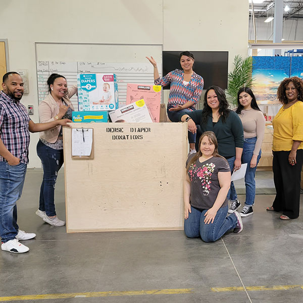 group of people by large collection bin of diapers in warehouse